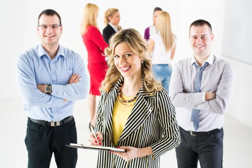 Group of business professionals smiling and holding clipboards in bright office as business directory lists your business